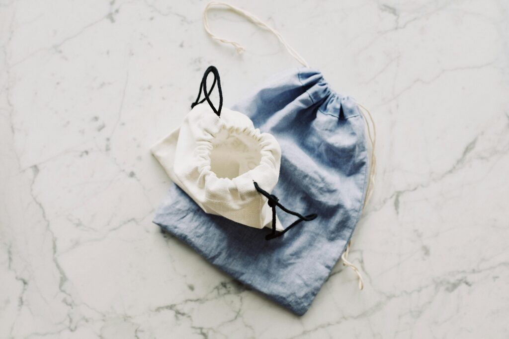Top view of blue and white textile bags placed on each other on marble surface in room